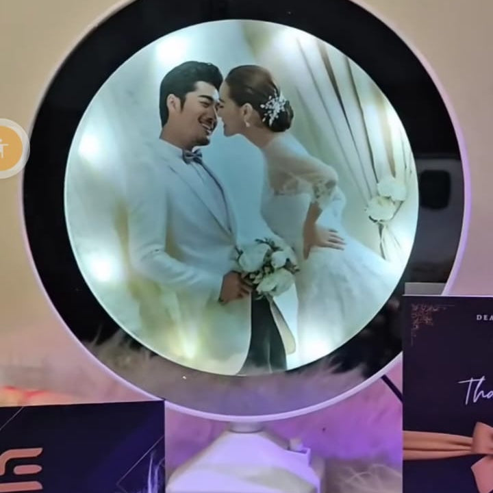 Circular photo of a couple in formal attire with a blurred background, placed on a white surface.