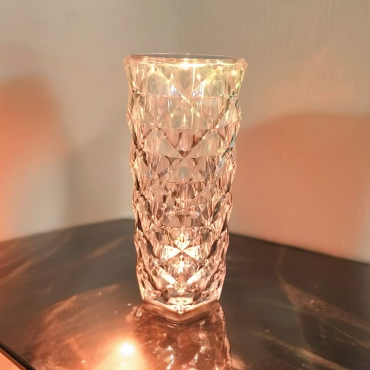 Decorative glass vase on a reflective surface with a blurred background