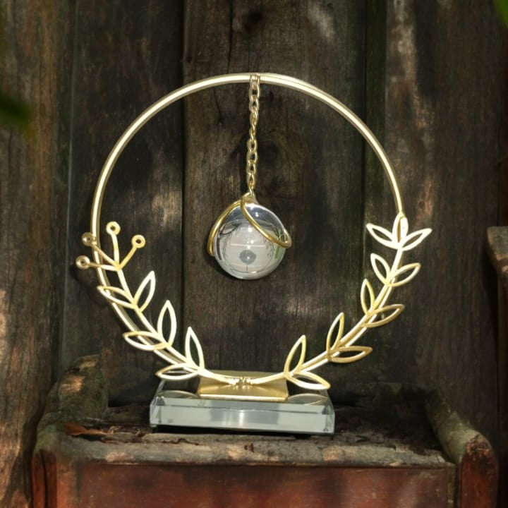 Decorative wreath with a clock in the center, set against a natural background of trees.