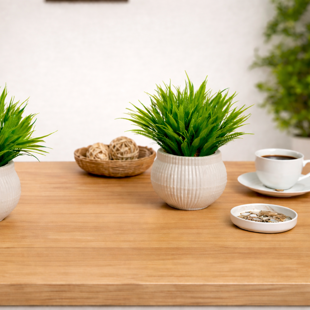 Two potted plants on a wooden desk with a notebook, pen, and coffee cup.